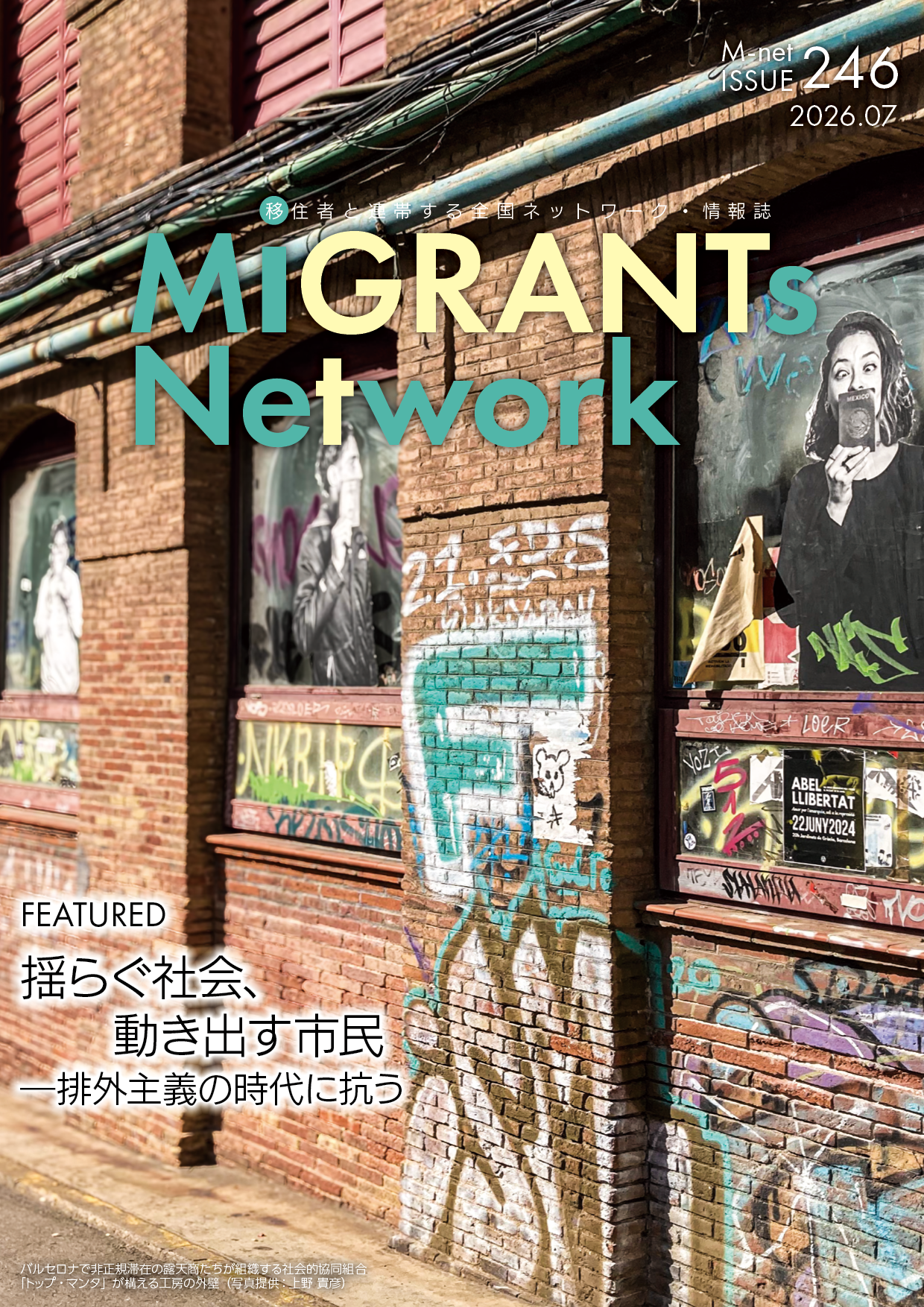 雑誌『MIGRANTs Network』2026年7月号(ISSUE 246)の表紙です。 背景は、バルセロナにある、落書きで覆われた古びた赤レンガの建物の外壁です。 レンガ壁や複数の窓は、青、白、黒など様々な色のグラフィティやポスターで埋め尽くされています。 右側の窓には、笑顔でパスポートのようなものを掲げる女性のポスターが貼られており、その下の窓枠には「ABEL TLIBERTAT」「22JUNY2024」と書かれた小さなポスターや落書きが見えます。 レンガ壁の中央には、大きな青緑色のグラフィティや、ミッキーマウスの落書きがあります。 上部には、ティールと黄色で大きく「MIGRANTs Network」というタイトルが2行で書かれています。 その上に、小さなテキストで「●移住者と連帯する全国ネットワーク・情報誌」「M-net ISSUE 246 2026.07」と書かれています。 左下には、大きなテキストで「FEATURED 揺らぐ社会、動き出す市民 —排外主義の時代に抗う」と書かれています。 左下の非常に小さなテキストは「バルセロナで非正規滞在の露天商たちが運営する社会的協同組合『トップ・マンタ』が構える工房の外観(写真提供:上野貴彦)」と書かれています。